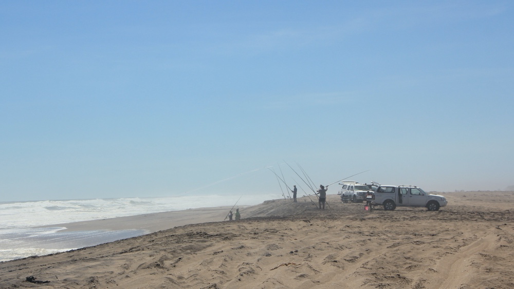 Fishermen and vehicles on the beach.